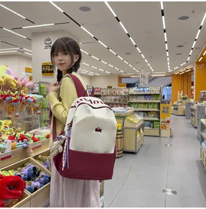 Detailed view of large capacity two-tone student school backpack with letter print and cute pendant.