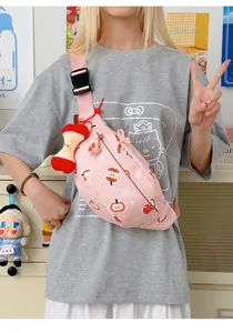Gros plan de la jolie sacoche de poitrine rose imprimée de pommes avec pendentif en peluche.
