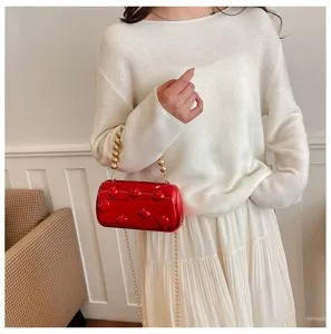 Nahaufnahme der glänzenden roten Acryl-Abendtasche mit goldener Perlenkette und Riemen.
