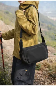 Vista detallada del bolso cruzado de trabajo negro usado al aire libre con correa ajustable.