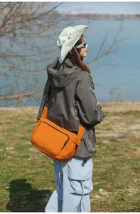 Vista detallada del bolso cruzado naranja al aire libre usado por el modelo, textura.