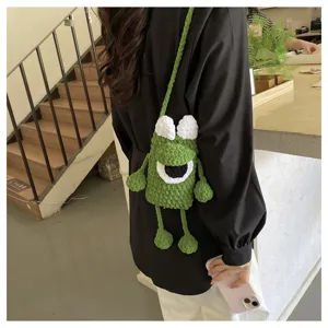 Handmade green knitted crossbody phone bag with cute monster design, cozy plush yarn accessory.