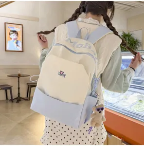 Detailed view of the color-block student backpack with cute bear keychain and letter embroidery.
