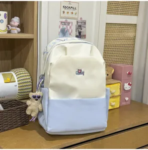 Canvas color-blocked school backpack with cute teddy bear keychain and large capacity for daily use.