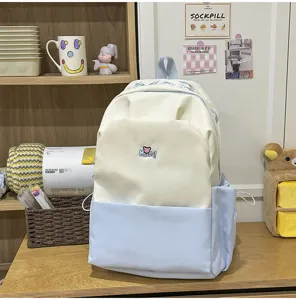 Detailed shot of a stylish contrast color school backpack in white and light blue with cute embroidery.