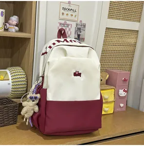 Two-tone large capacity student backpack with cute bear pendant and stylish embroidery details.
