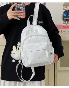Gedetailleerd overzicht van de witte mini-rugzak met zilveren sterrenprint en pluizige hanger.