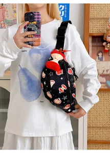 Vue détaillée du sac bandoulière noir avec imprimé pomme mignon et charm peluche ludique.