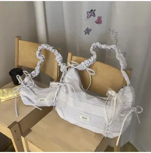 Gedetailleerd uitzicht op de esthetische paarse ruitjes geplooide schoudertas met strikjes.