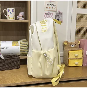 White and yellow colorblock student backpack with spacious capacity and convenient drawstring front pocket.