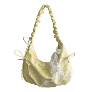 Detail van de geel gestreepte hobo schoudertas met geplooide schouderband en kant strik hanger.