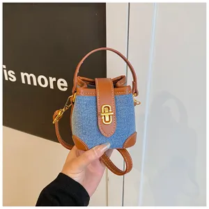 Λεπτομέρεια μίνι τσάντας κάδος denim με καφέ δερμάτινο τελείωμα, χρυσό κλειδί και άνω λαβή.