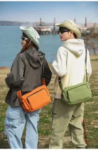 Vista de detalle de estilo de vida al aire libre de bolsos cruzados utilitarios naranjas.