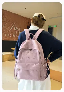 Detailansicht eines rosa minimalistischen Schulrucksacks mit niedlichen Schleifen und Vordertasche.