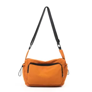 Bolso cruzado de lona naranja con correa de hombro negra y bolsillo con cremallera.