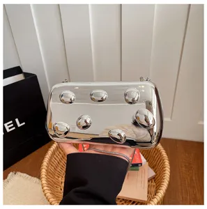 Nahaufnahme einer glänzenden silbernen Metall-Box-Clutch mit erhabenem Punktmuster.
