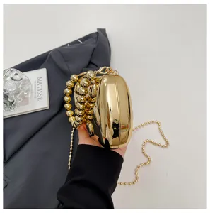 Goldene Abendtasche Detailansicht mit glänzender metallischer Oberfläche und eleganter Perlenkette.