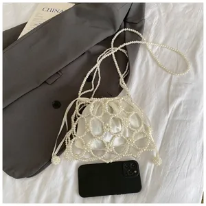 Detailed shot of white pearl beaded mesh crossbody bag with drawstring lining on styled flat lay.
