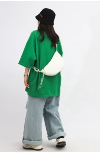 Detailed view of a trendy white crescent crossbody dumpling bag worn by a model from behind.