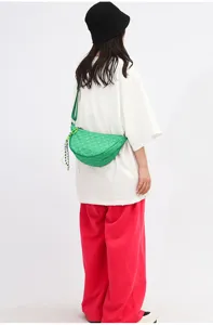 Detailed shot of a stylish green woven nylon dumpling crossbody bag worn by a model in streetwear style.