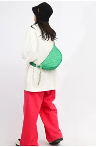 Green woven nylon dumpling crossbody bag worn by female model with casual outfit style