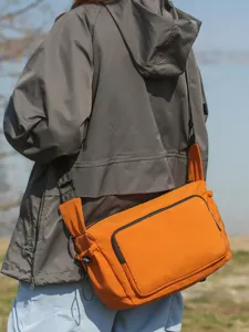Bolso bandolera workwear de moda, bolso crossbody de lona naranja para hombre y mujer al aire.