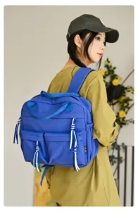 Vue détaillée du sac à dos en nylon bleu élégant porté, montrant les poches avant.