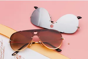 Detailed shot of stylish one-piece aviator sunglasses with hollow circular design and colored mirror.