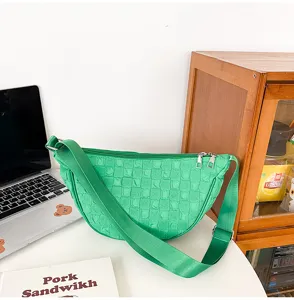 Green quilted crescent crossbody bag detail showcasing its soft nylon fabric and grid pattern.