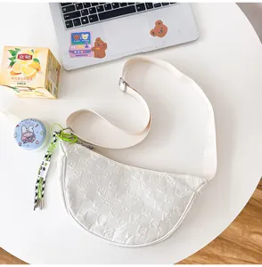 White nylon crescent crossbody shoulder bag with adjustable strap and cute pendant detail