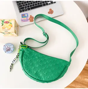 Green nylon crescent crossbody bag with chic quilted pattern and adjustable shoulder strap.