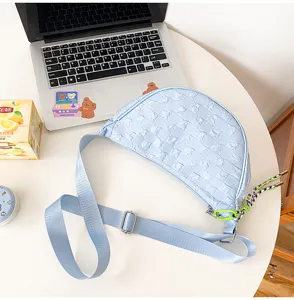 Light blue nylon crescent cross-body bag with grid texture and adjustable strap for daily wear.