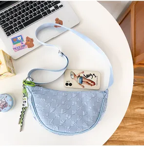 Detailed view of the light blue nylon crescent shoulder bag with textured pattern.