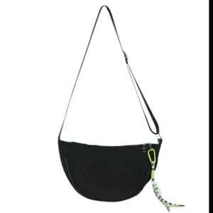 Close-up detail of black nylon crescent dumpling shoulder bag with adjustable strap and charm.