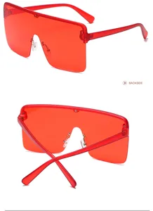 Vue detaillee des lunettes de soleil rouges monobloc oversize avec monture carree sans contour.