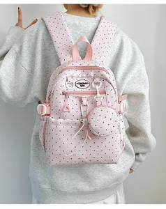 Gros plan détaillé d'un joli sac à dos d'école à pois roses avec une mini pochette.
