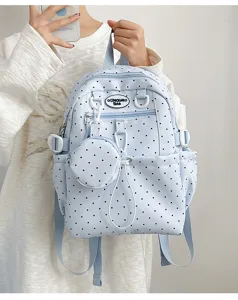 Vue détaillée d'un joli sac à dos bleu clair à pois avec petite pochette ronde et poches.