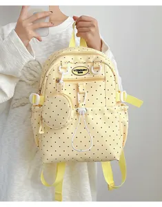 Détail du sac à dos jaune à pois avec poche avant et conception de cordon de serrage.