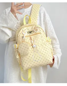 Gros plan détaillé du sac à dos jaune à pois avec une poche avant et une petite pochette ronde.