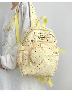 Détail de sac à dos à pois jaunes avec poche latérale, bretelles et petite pochette.