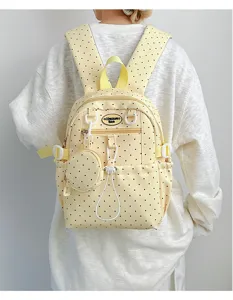 Vue détaillée du joli sac à dos à pois jaunes avec une mini pochette et des bretelles.