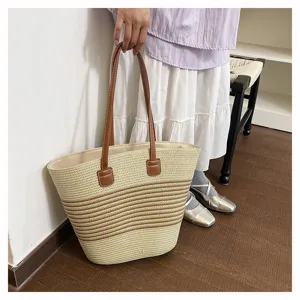 Detailed view of the woven straw tote bag featuring contrast stripes and brown handles.