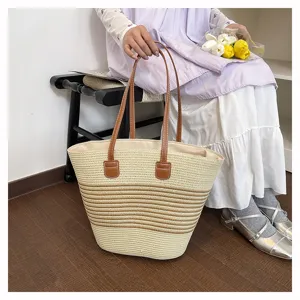 Detailed view of women's woven straw tote bag, casual beach style with contrast handles.