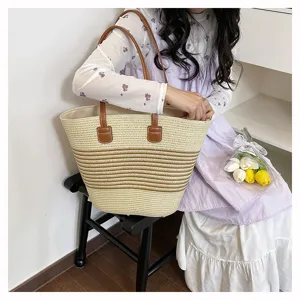 Straw woven tote bag featuring contrast brown stripes and PU leather handles for daily commute.