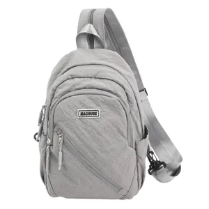 Gros plan détaillé du sac à dos bandoulière en nylon gris avec poche et étiquette.
