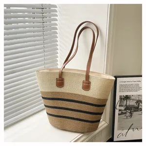 Woven straw tote bag with color-block stripes and brown leather handles for beach vacation.