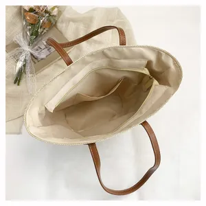 Detailed top view of straw tote bag interior showing durable lining, zipper pocket, and handles.
