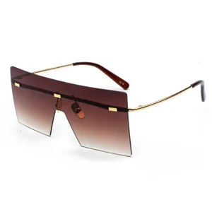 Gafas de sol oversize con parte superior plana, lentes marrones degradadas y finas varillas doradas.