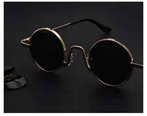 Nahaufnahme von retro runden Sonnenbrillen mit goldenem Metallrahmen und schwarzen Gläsern.