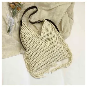 Gros plan détaillé sur le sac bandoulière crocheté beige avec franges et lanière marron.
